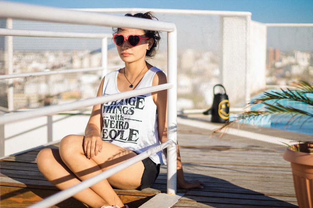 woman sitting on stair beside fence