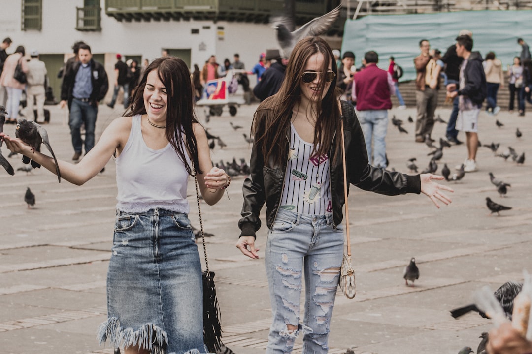 two women standing near pigeons