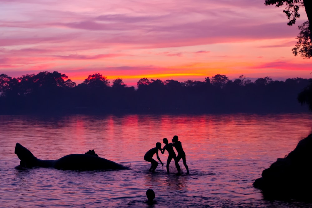 silhouette of children playing on lake
