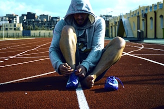 An athlete tying running shoes before dawn on a city rooftop.