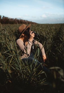 woman taking photo while sitting on green grass field