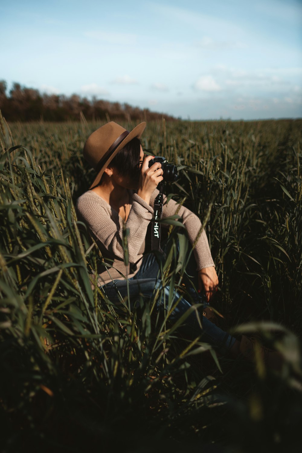 mulher tirando foto enquanto está sentada no campo de grama verde