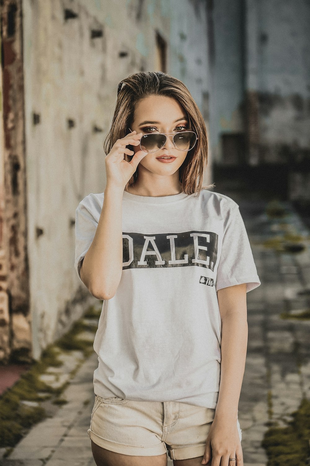 woman in white top holding sunglasses