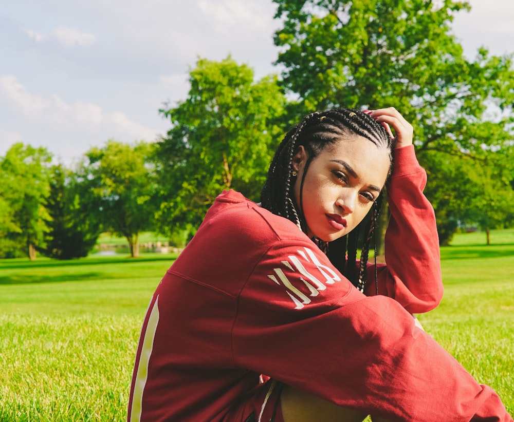 closeup photo of woman sitting on ground holding her haid