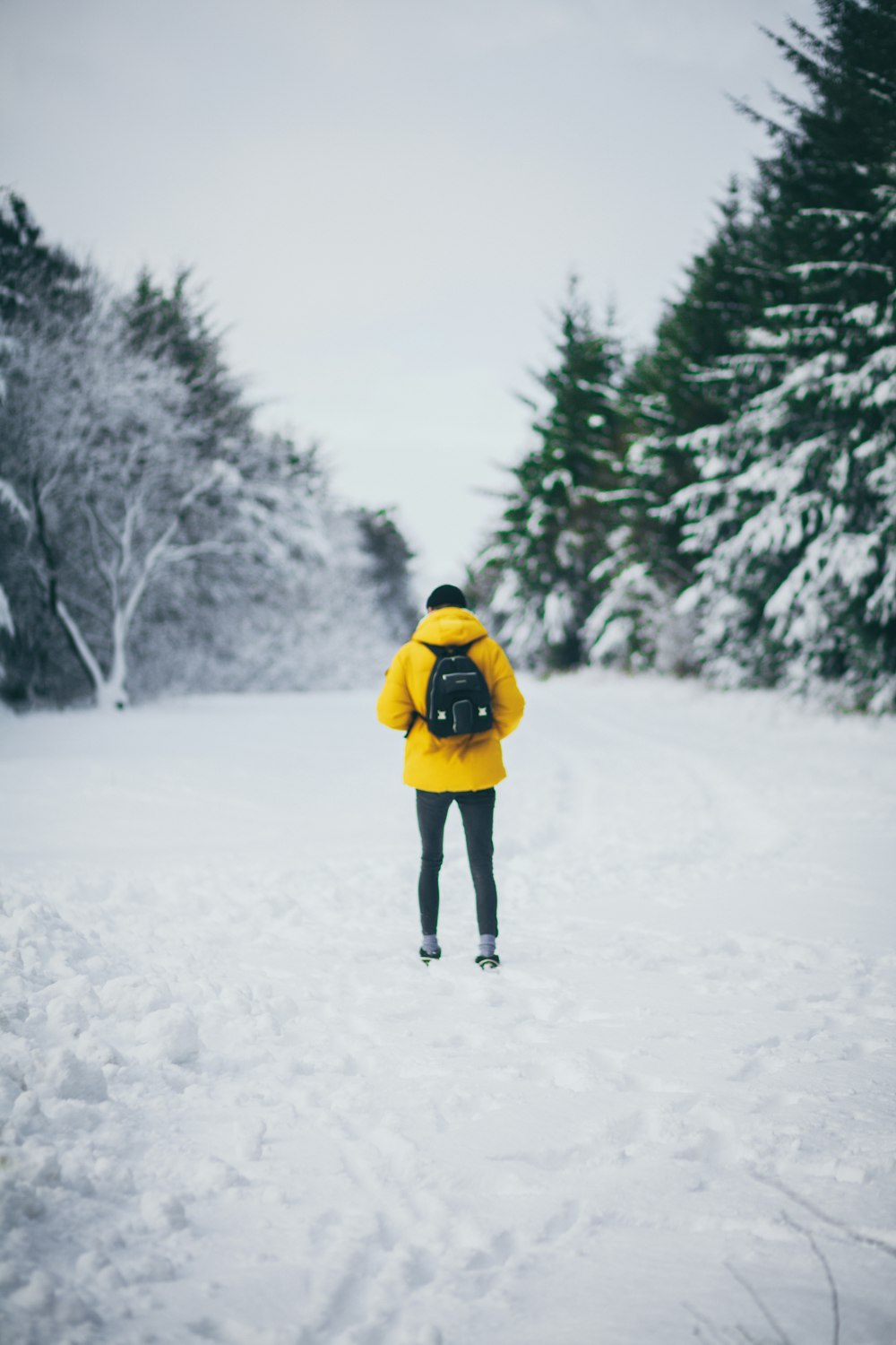 Mann, der tagsüber auf einem Schneefeld steht und einen Rucksack trägt