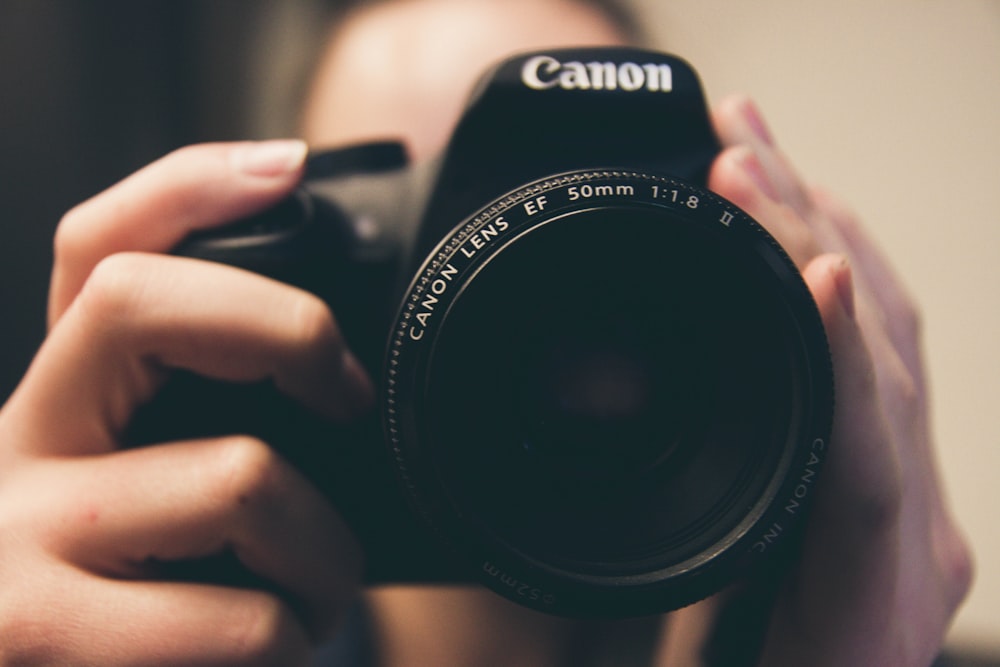 fotografía de enfoque superficial de una persona que toma una foto con una cámara Canon DSLR