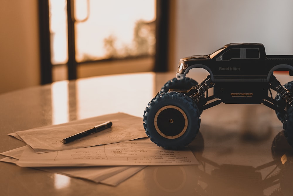 jouet monster truck noir sur table en bois blanc