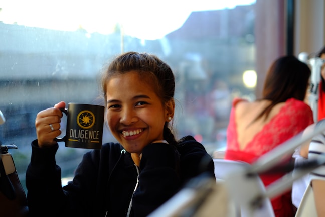 A smiling woman wearing a soft dancuthy t-shirt, holding a colorful mug.