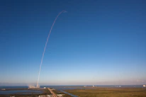 Close-up of a SpaceX rocket launching into a clear blue sky.