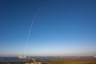 A vibrant rocket lifting off against a clear blue sky at dawn.