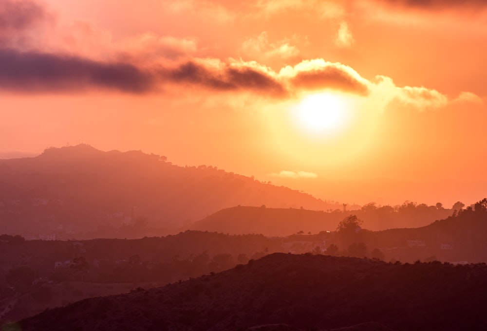 silhouette photo of mountains by the setting of the sun