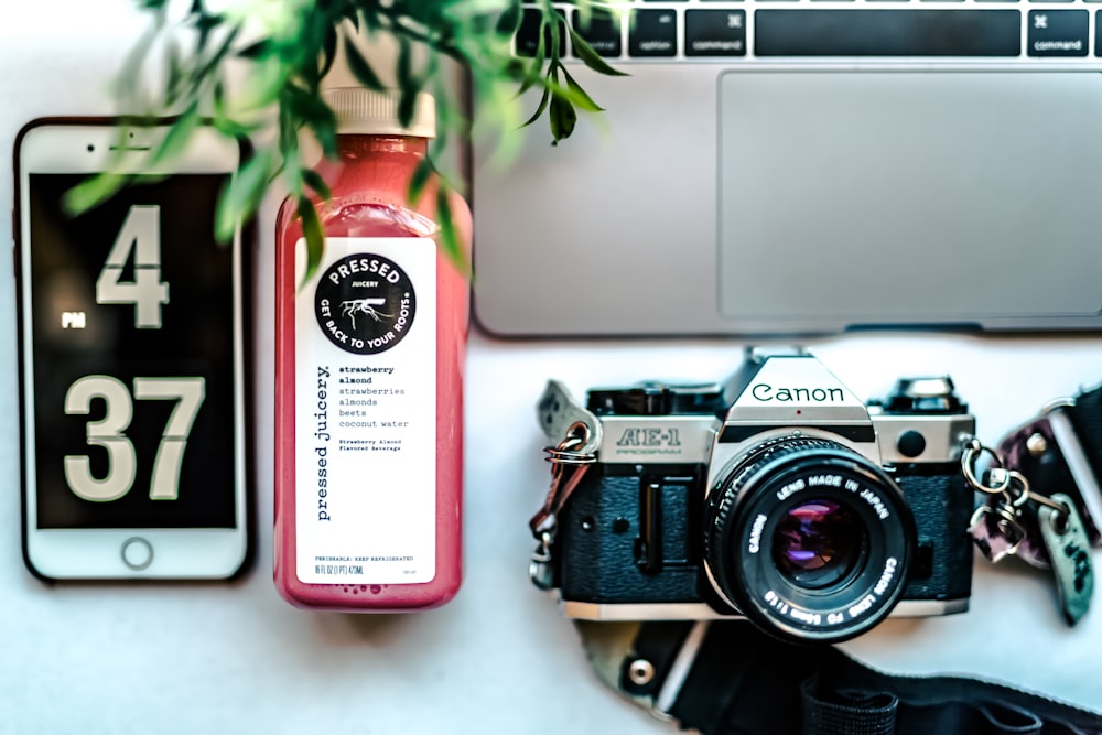 Appareil photo Canon MILC gris et noir près de la bouteille étiquetée