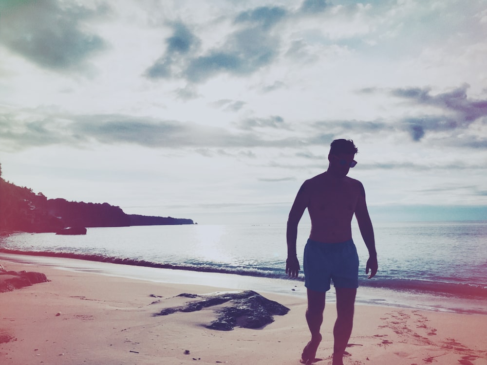 man walking on brown sand under gray sky during daytime