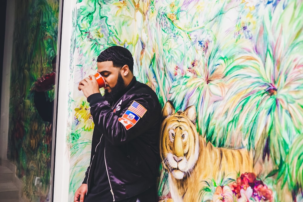 man leaning on tiger painted wall