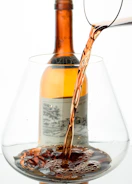 Close-up of a wine glass being poured from a bottle labeled with local East African motifs.