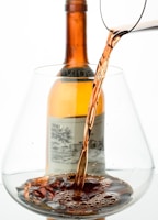 Close-up of a master distiller’s hands carefully pouring amber spirit into a crystal glass under warm, moody lighting.