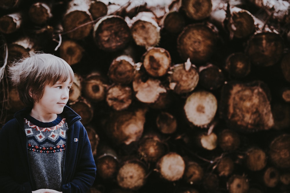 boy standing under cut wood log background