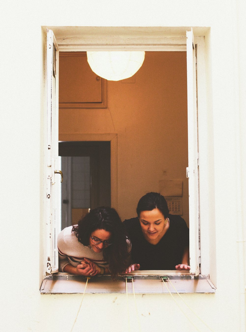 two woman looking through window
