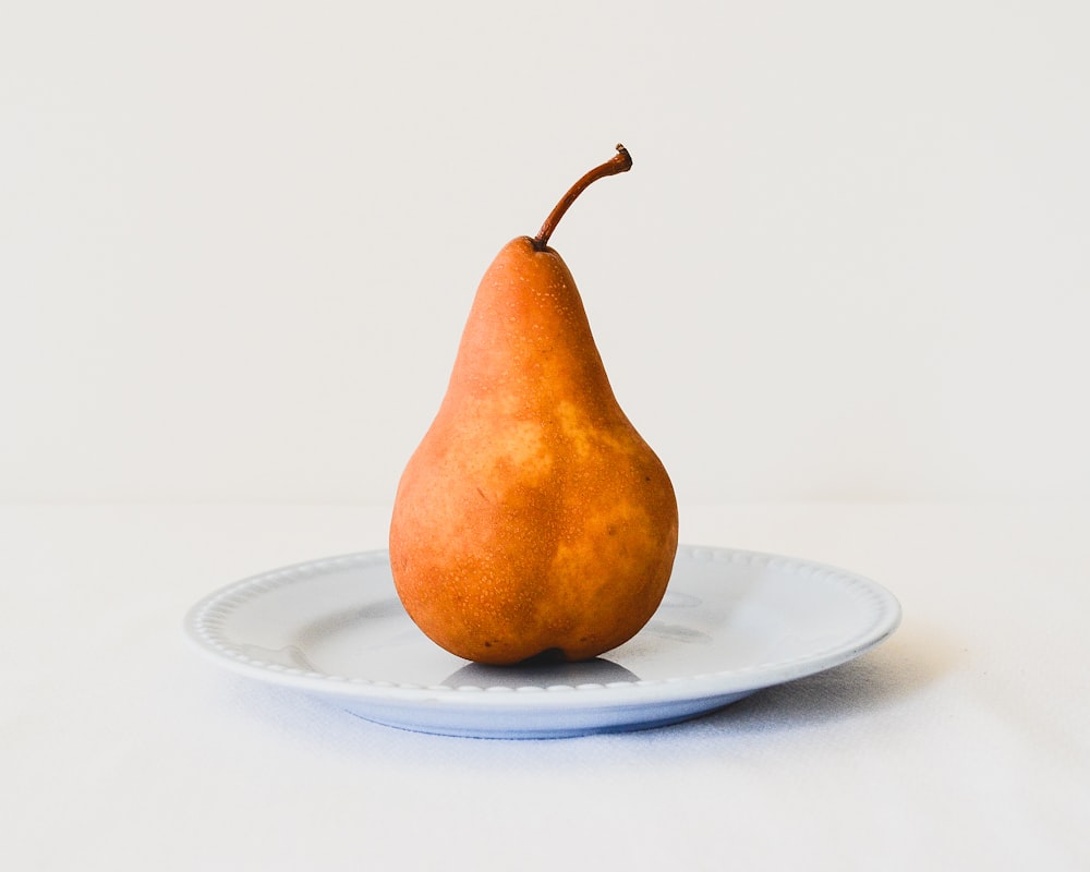pera arancione su piatto in ceramica bianca