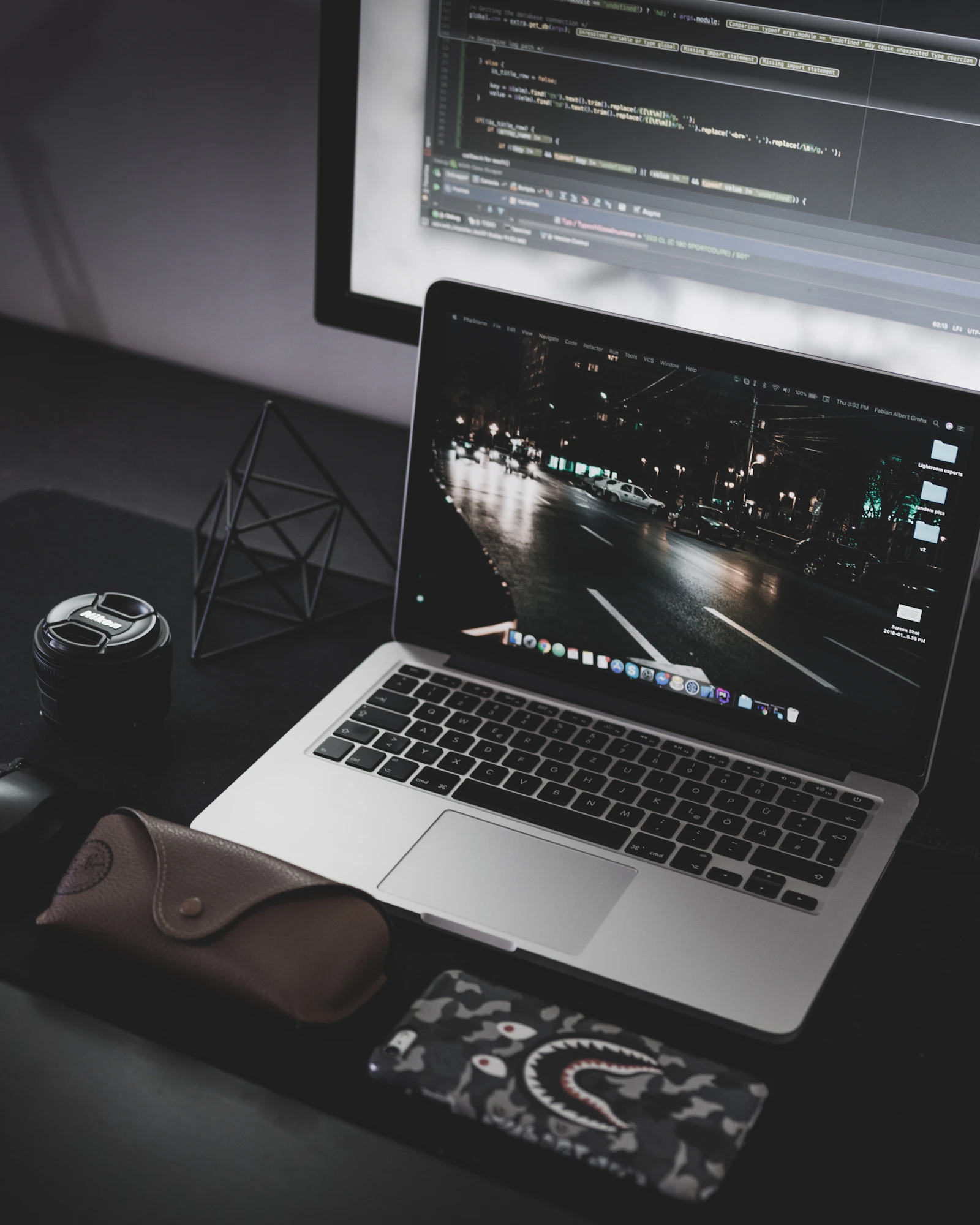 Minimalist dark developer workstation showing laptop screen and code development environment