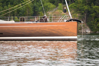 Close-up of a polished boat hull reflecting sunlight on a calm marina.
