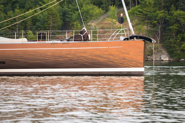 Close-up of a polished boat hull reflecting sunlight on a calm marina.