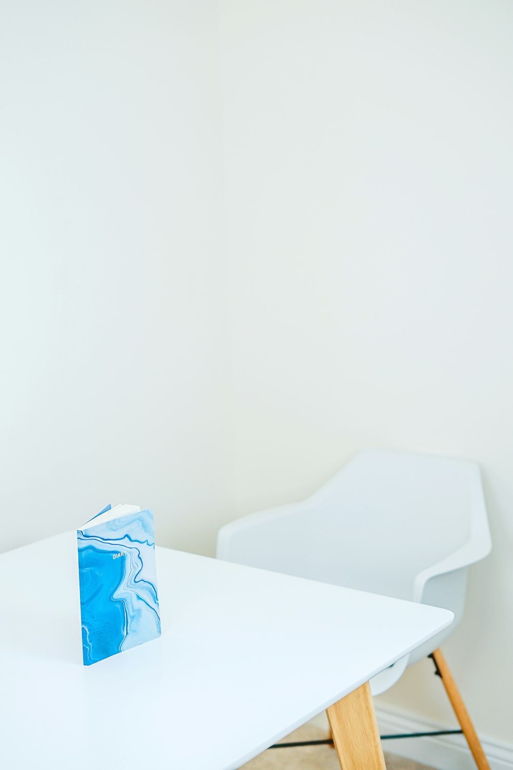 blue and white hardbound book on white wooden table