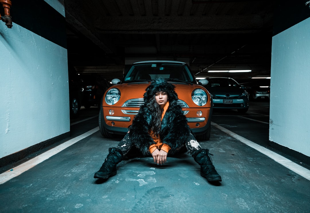 woman sitting on pavement near car