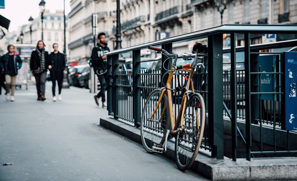 bicicleta laranja estacionada nas grades do metrô