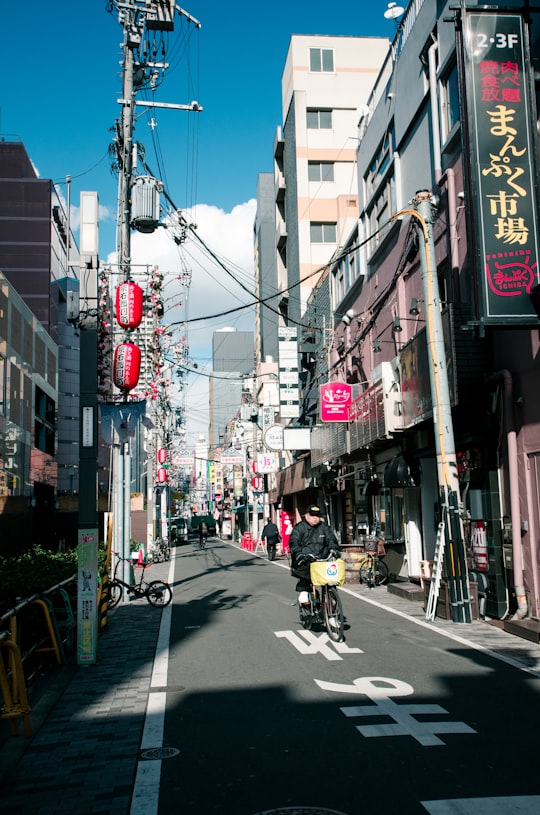 man riding bike on road in Nipponbashi Japan