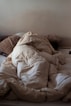 an unmade bed with a white comforter on top of it