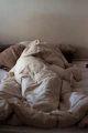 an unmade bed with a white comforter on top of it
