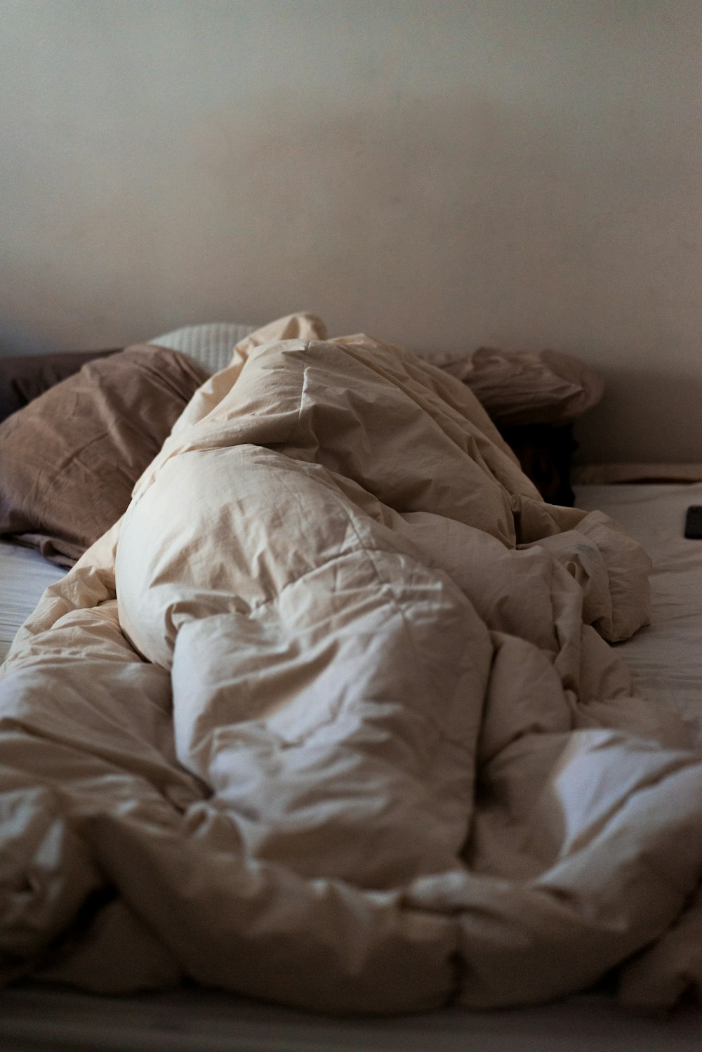 an unmade bed with a white comforter on top of it