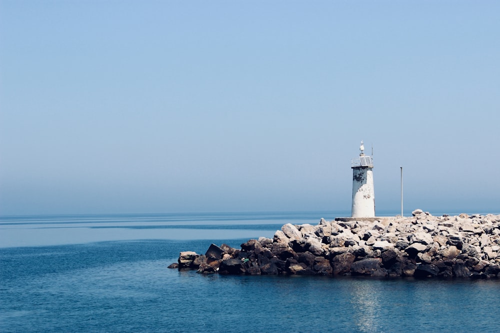 photograph of white lighthouse on rocks