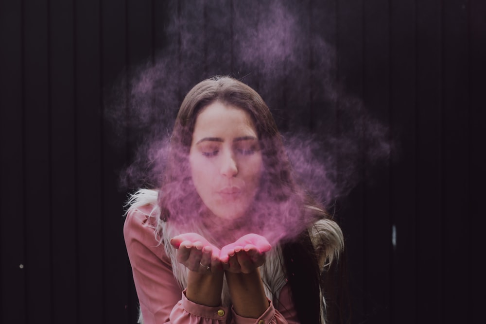 Mujer soplando humo en sus dos manos