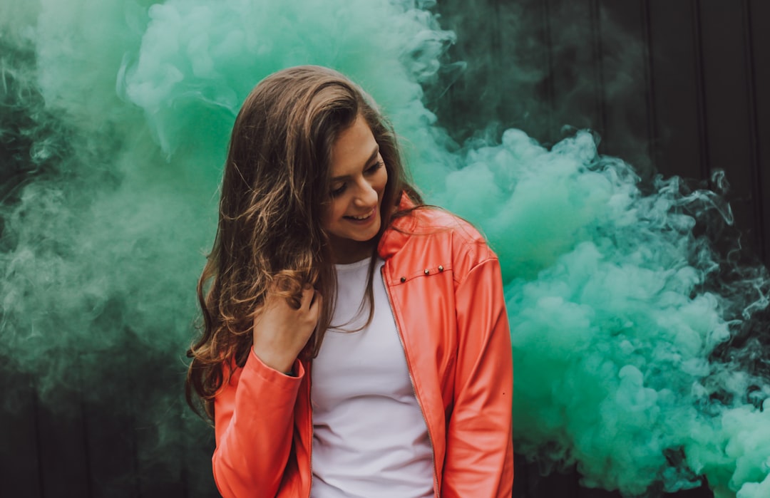 woman wearing orange leather jacket surrounded by green smoke