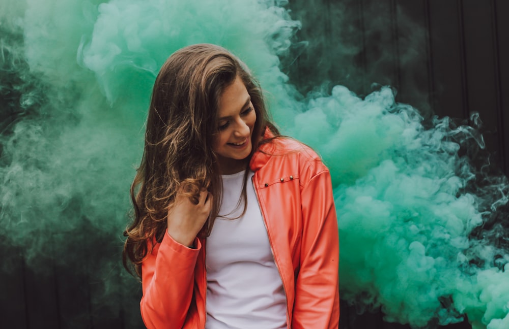 woman wearing orange leather jacket surrounded by green smoke