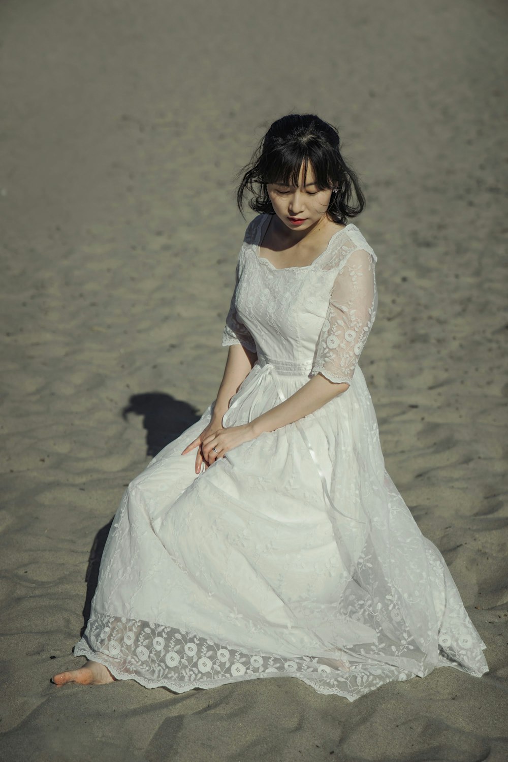 femme assise sur le sable gris