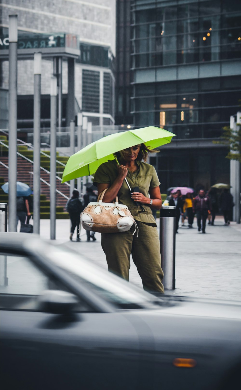 通りを歩く緑の傘を持つ女性