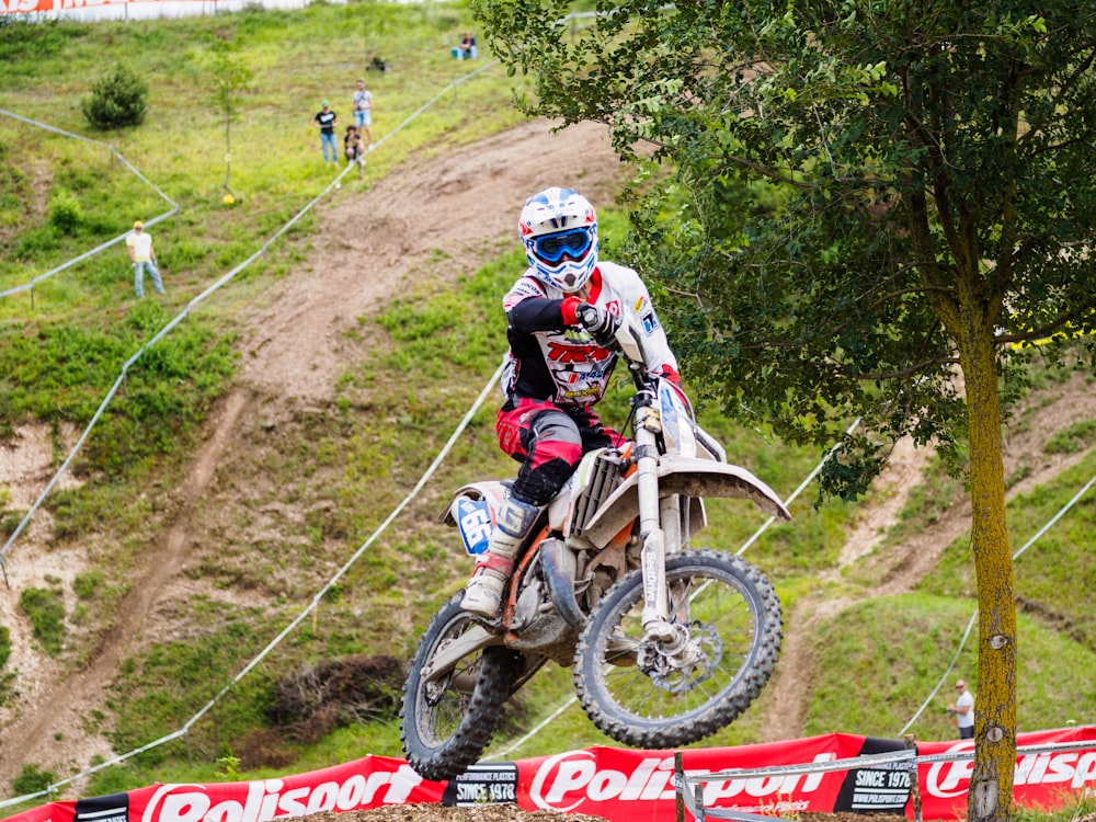 person riding dirt bike near green tree