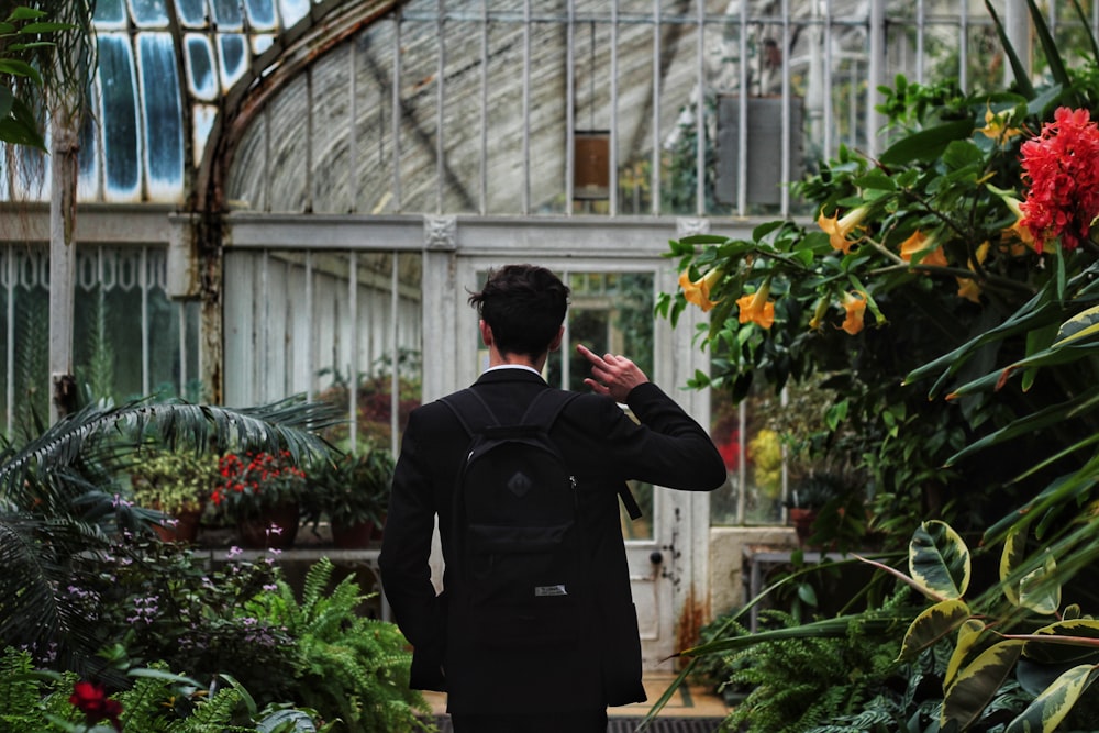 man standing surrounded by plants raising his hands