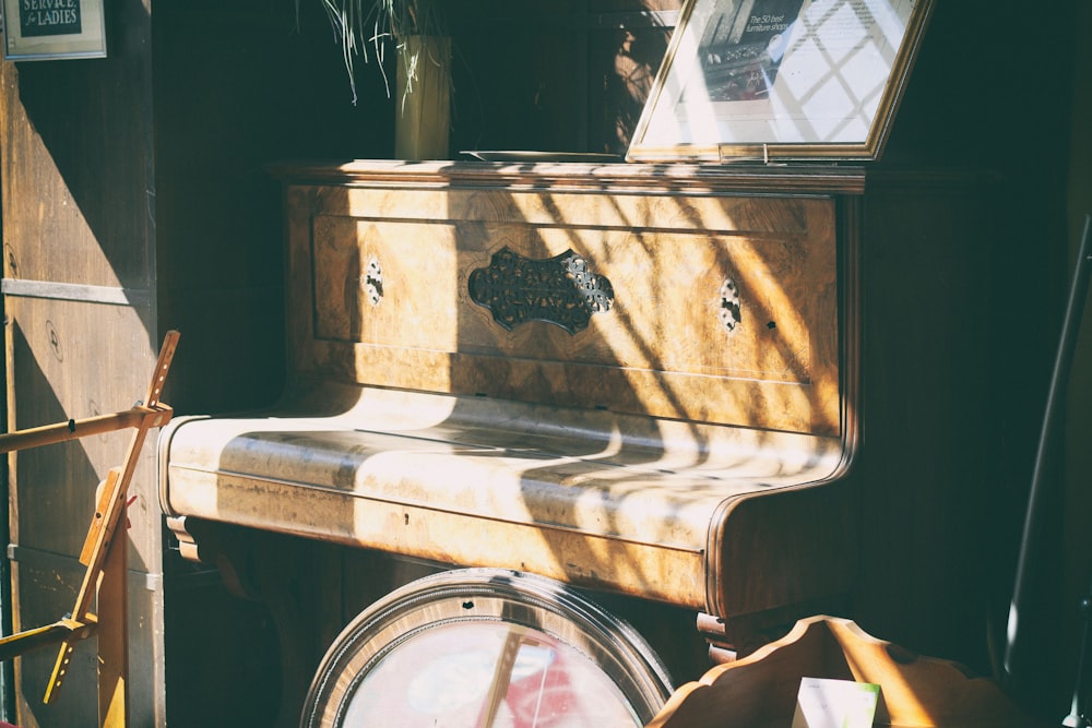 pianoforte verticale in legno marrone all'interno della stanza durante il giorno