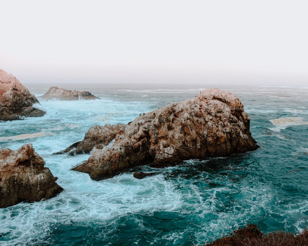 brown rock formation on body of water