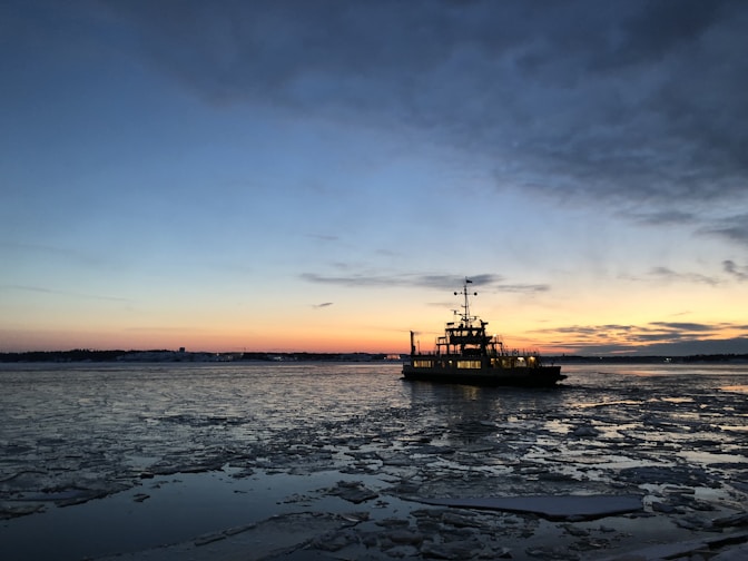silhouette photo of a vessel on body of water