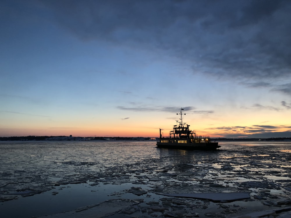 silhouette photo of a vessel on body of water