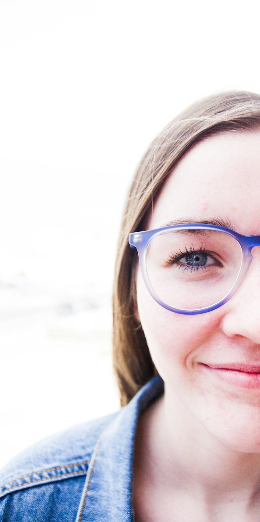 woman wearing blue framed eyeglasses and denim jacket