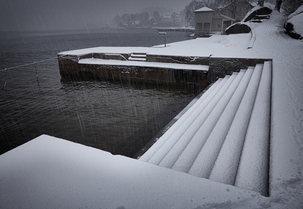 staircase covered in snow near body of water