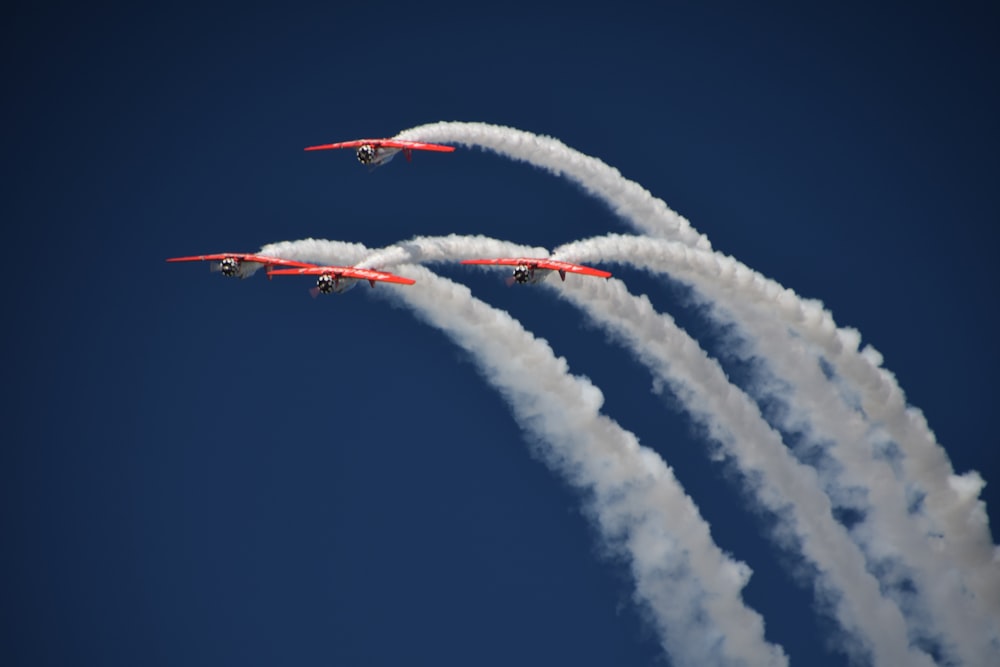 Vier rote Flugzeuge mit Kondensstreifen