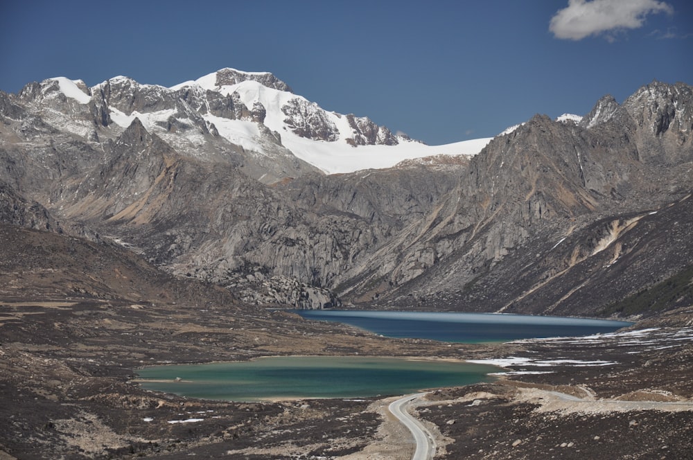 two lakes near road in distant of snow capped mountain