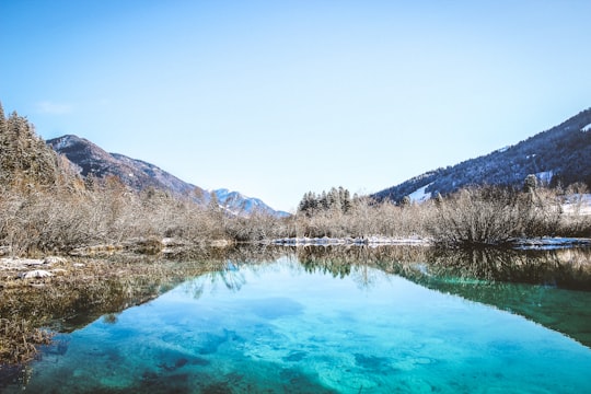 body of water surrounded by mountain range in Zelenci Slovenia